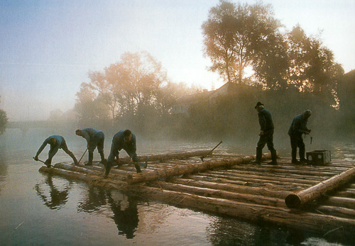 Flößer beim Zusammenbau des Holzflosses im Morgennebel an der Loisach
